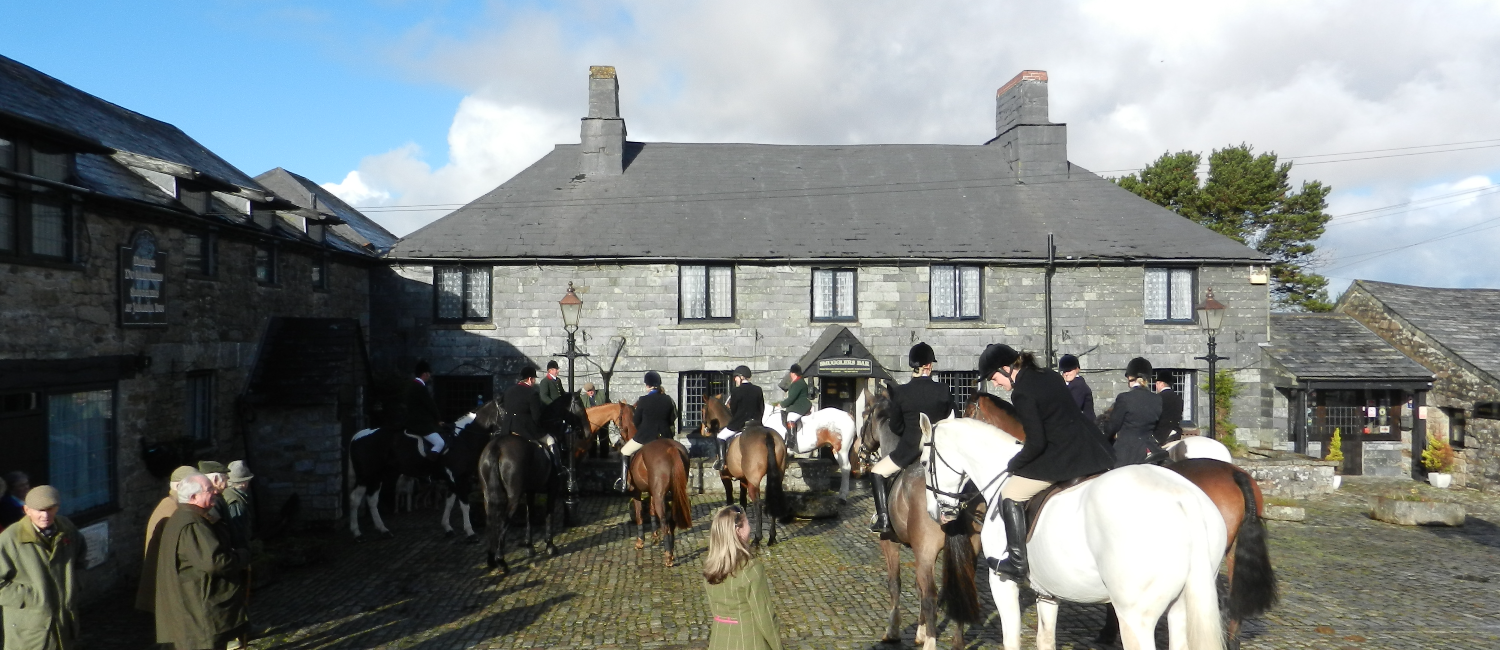 Horses and people mill about in a courtyard in the sun